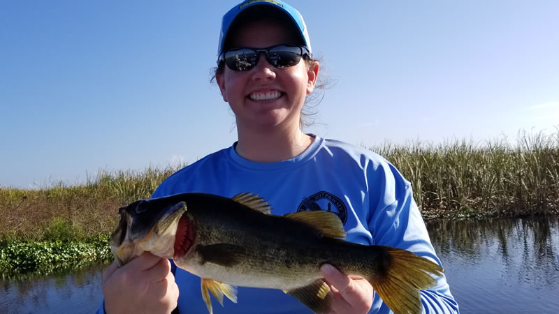 Woman holding a largemouth bass during a November Okeechobee City trip