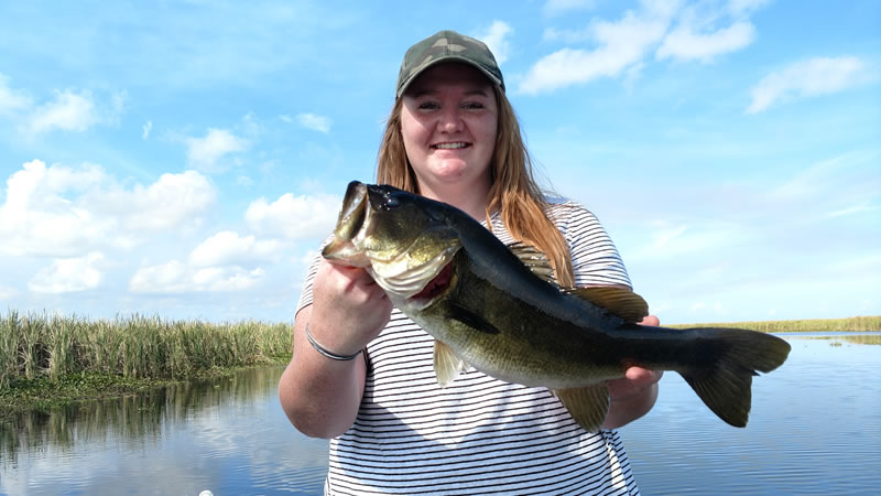 Woman holding a largemouth bass during a November Belle Glade trip