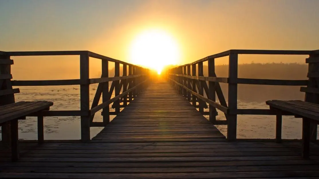 Sunrise at a wooden pier ideal for dock fishing for bass and peaceful reflection.