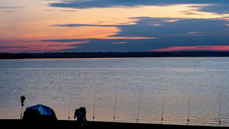 Lakeside sunset with tent and fishing rods, illustrating top fishing and camping combos in the southeast.