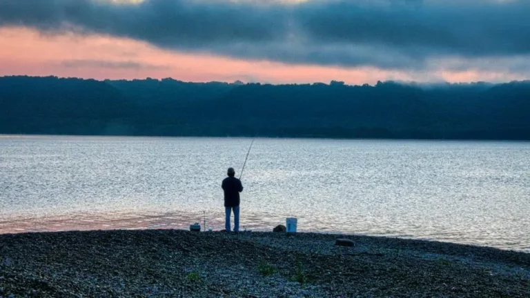 Fisherman at sunrise casting from Lake Monroe shore, perfect for learning how to fish Lake Monroe from shore.