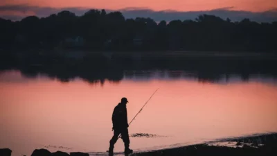 Fisherman at sunrise on Lake Tarpon, highlighting the fishing season's tranquil start.