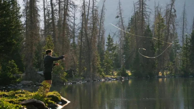 Angler flipping and pitching for bass in a serene alpine lake at sunrise.