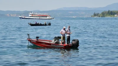 Anglers trolling for freshwater bass on Lake Garda with boats and mountain scenery in the background